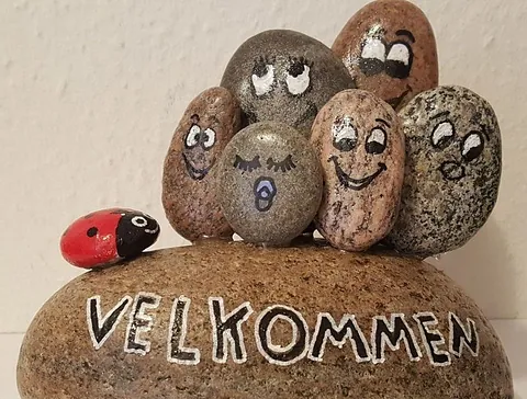 Sten med ansigter og velkommen skrevet på